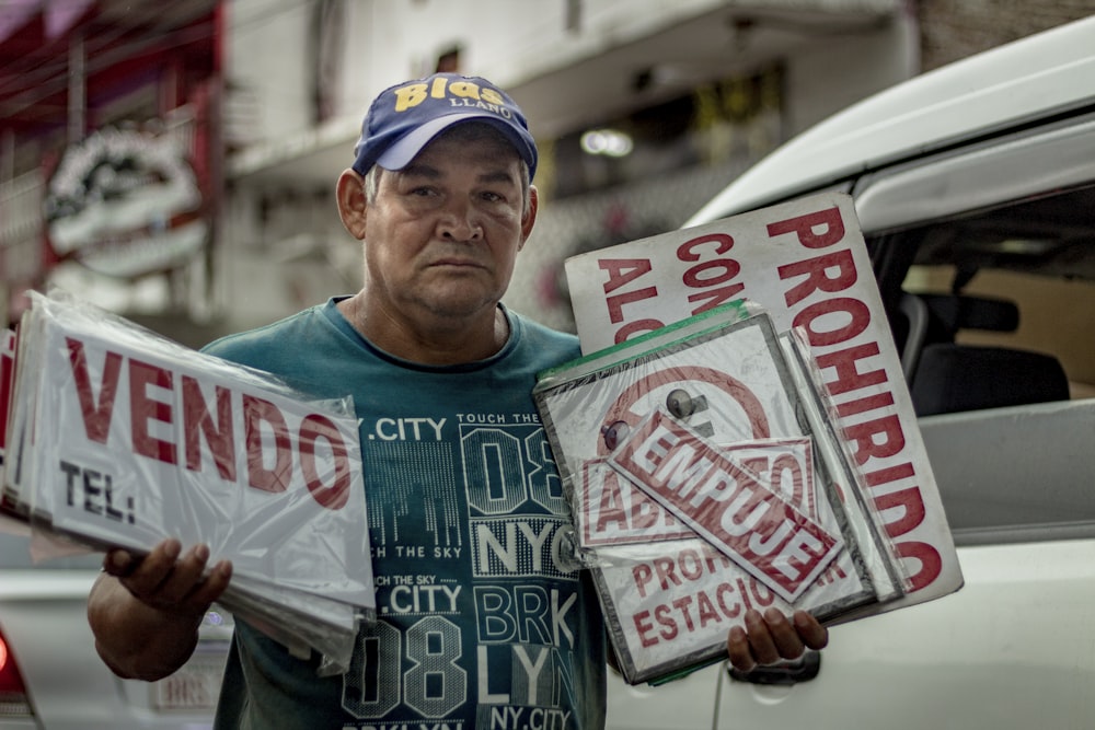 a man holding two signs in front of a car