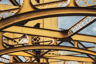 brown metal bridge under white clouds during daytime