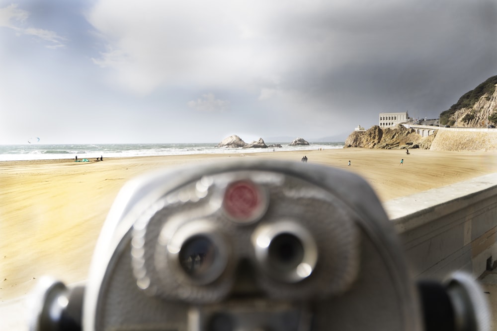 gray coin operated binoculars on brown sand during daytime