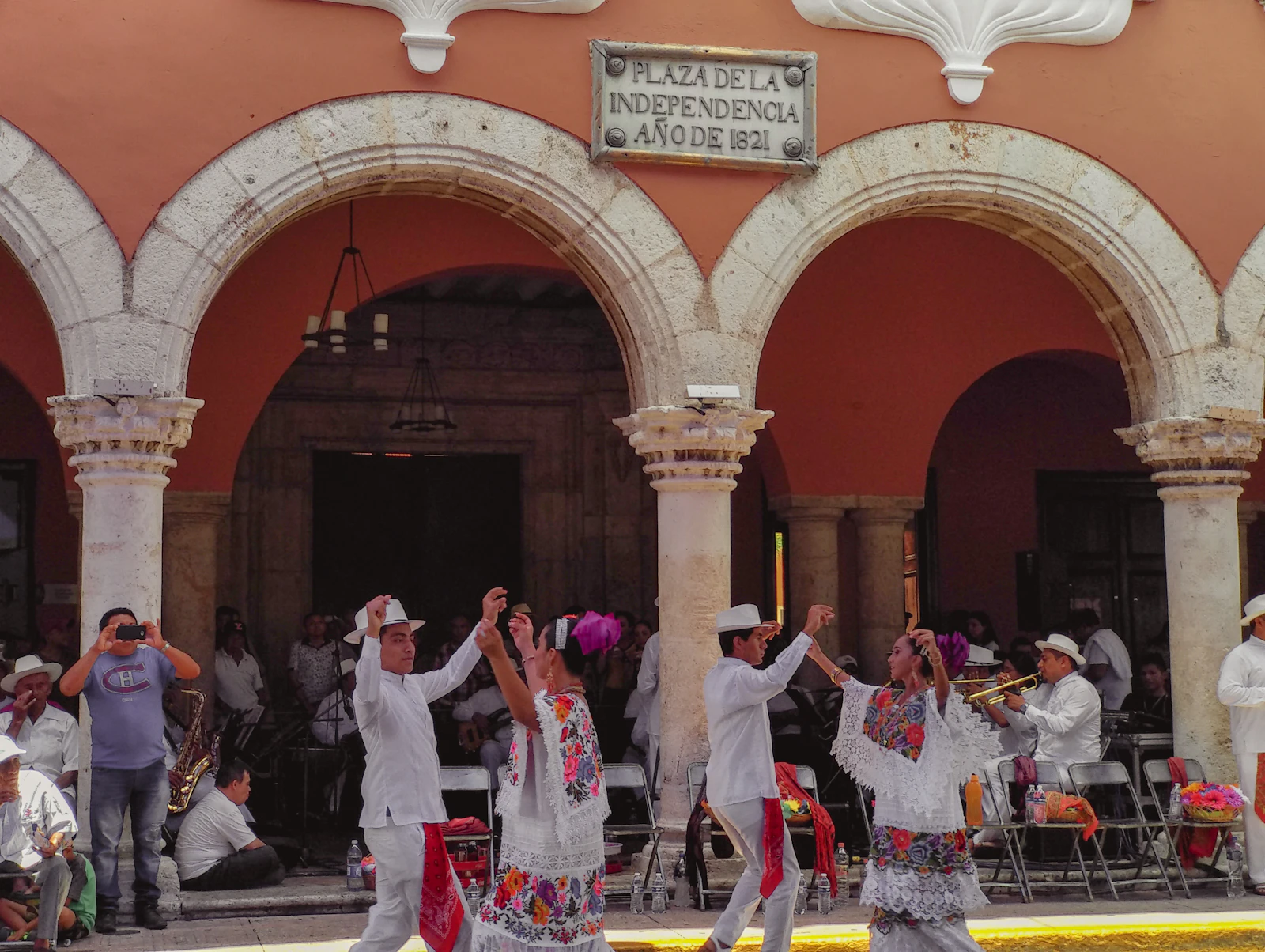 Dancers in white under the red arcades of a colonial building in Mérida