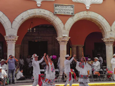 Dancers in white under the red arcades of a colonial building in Mérida