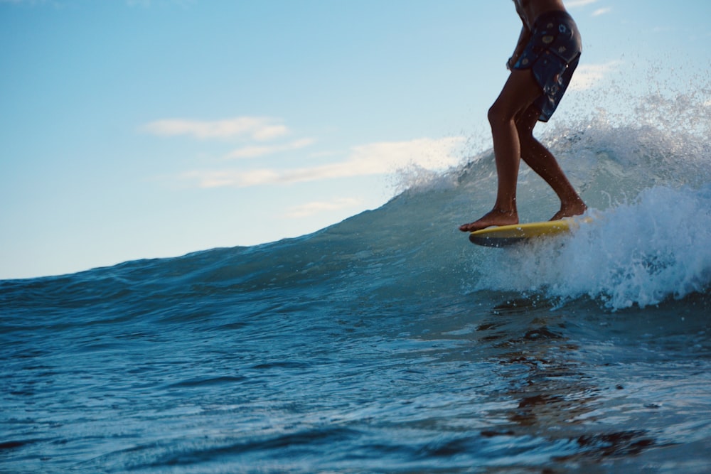 woman in blue and white bikini riding yellow surfboard on water during daytime