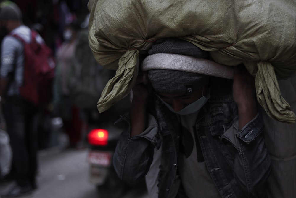 person in green jacket covering face with white and black scarf