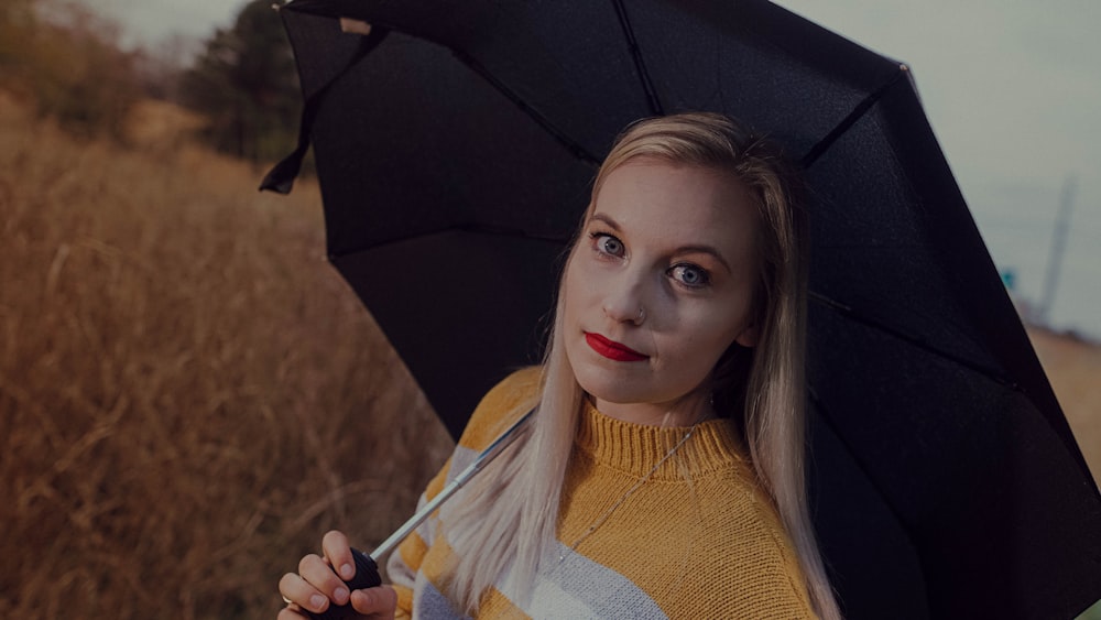 woman in white and yellow sweater holding umbrella