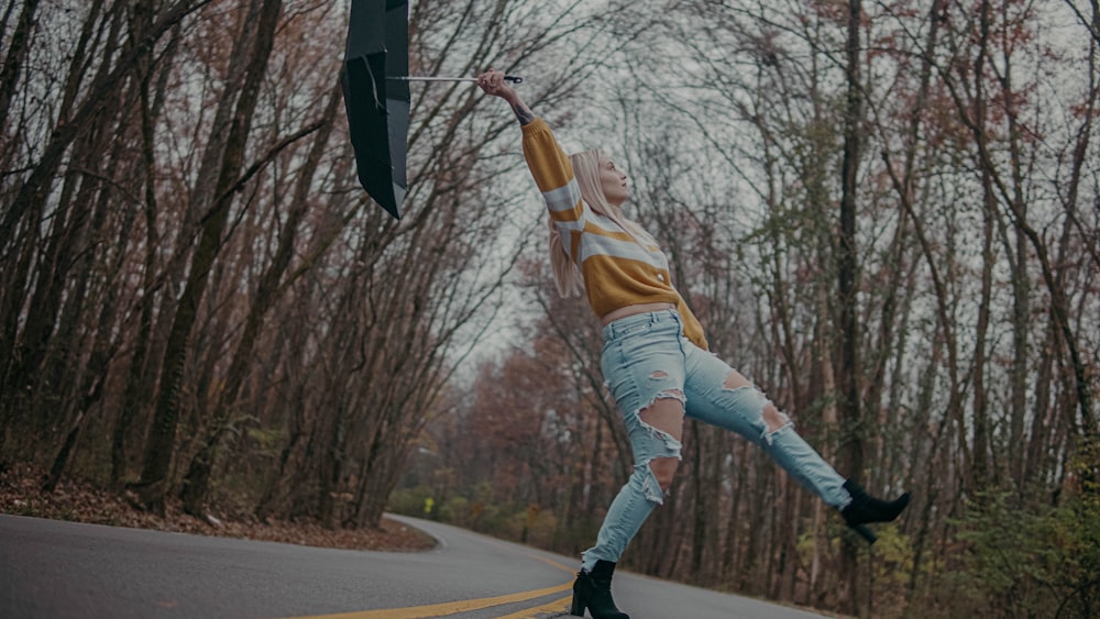 femme en chemise marron et pantalon blanc sautant sur la route pendant la journée
