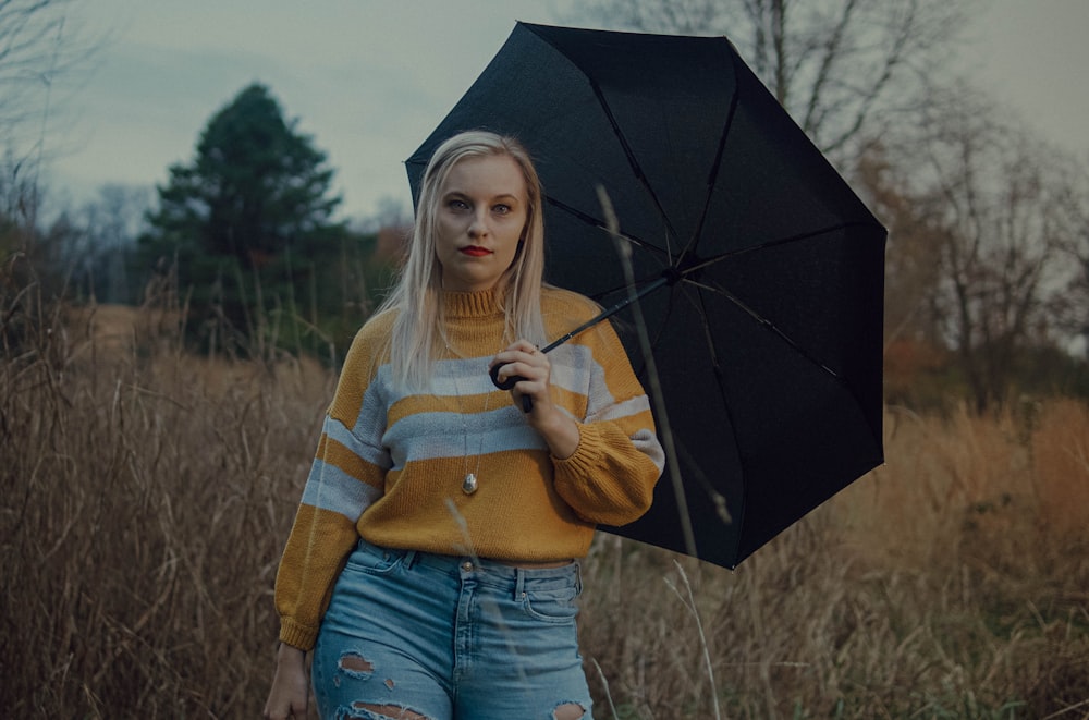 woman in brown and white striped sweater holding umbrella