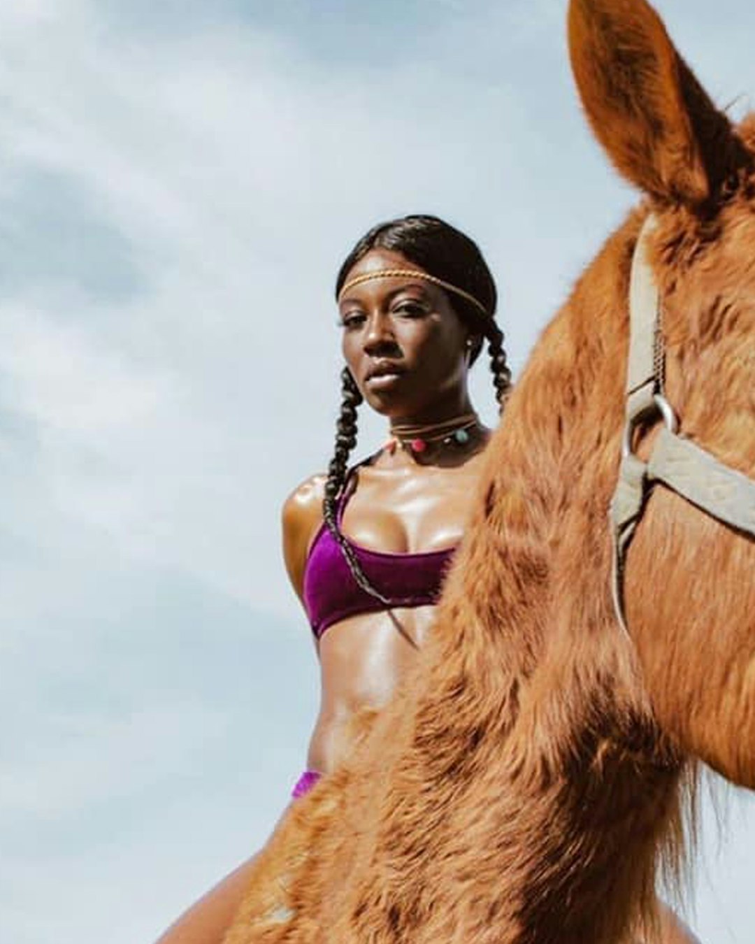 woman in pink brassiere riding brown horse under white clouds during daytime