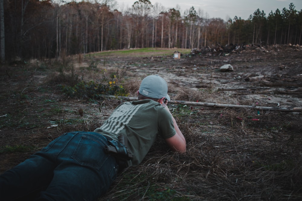 man in green jacket and blue denim jeans sitting on ground