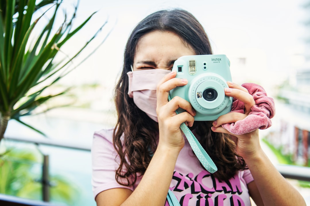 woman in white and pink shirt holding white and black camera