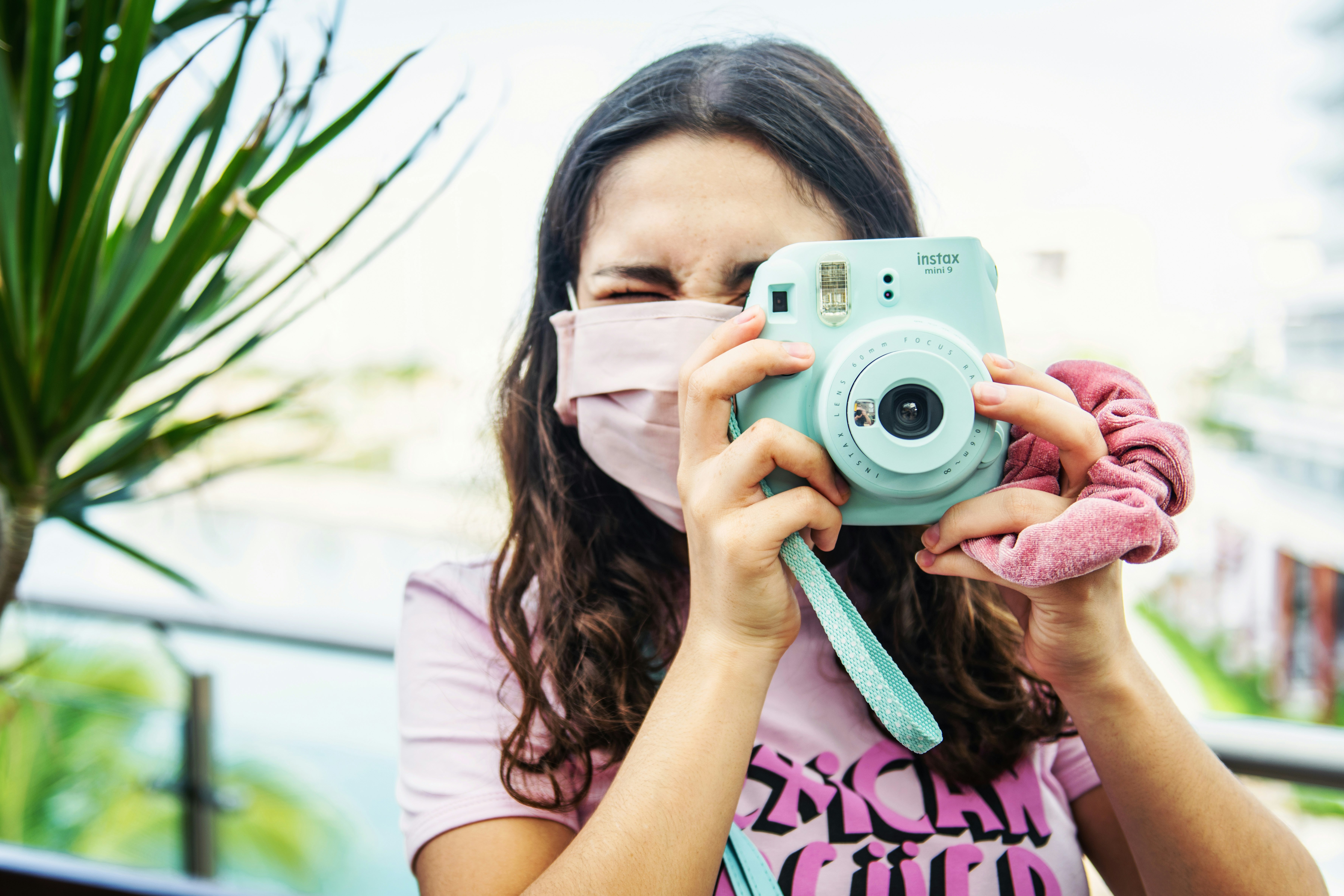 woman in white and pink shirt holding white and black camera