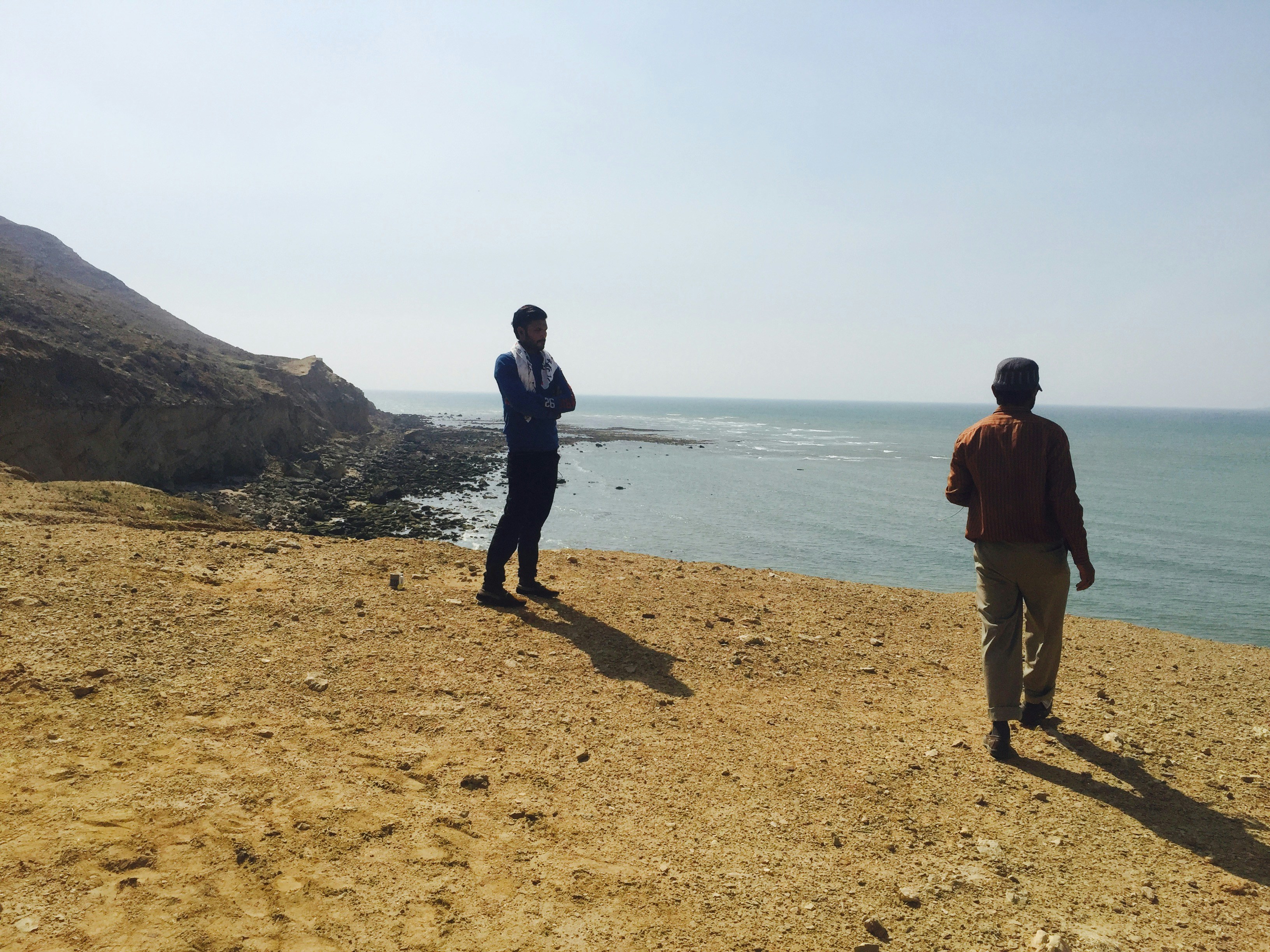 a couple of men standing on top of a sandy beach