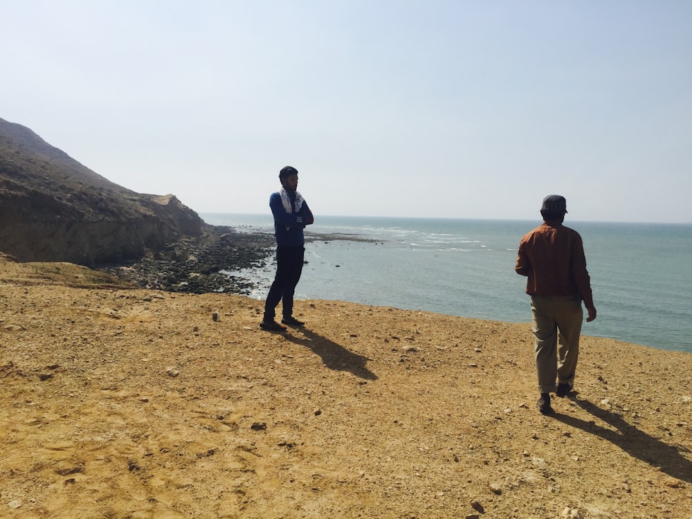 um casal de homens em pé em cima de uma praia de areia