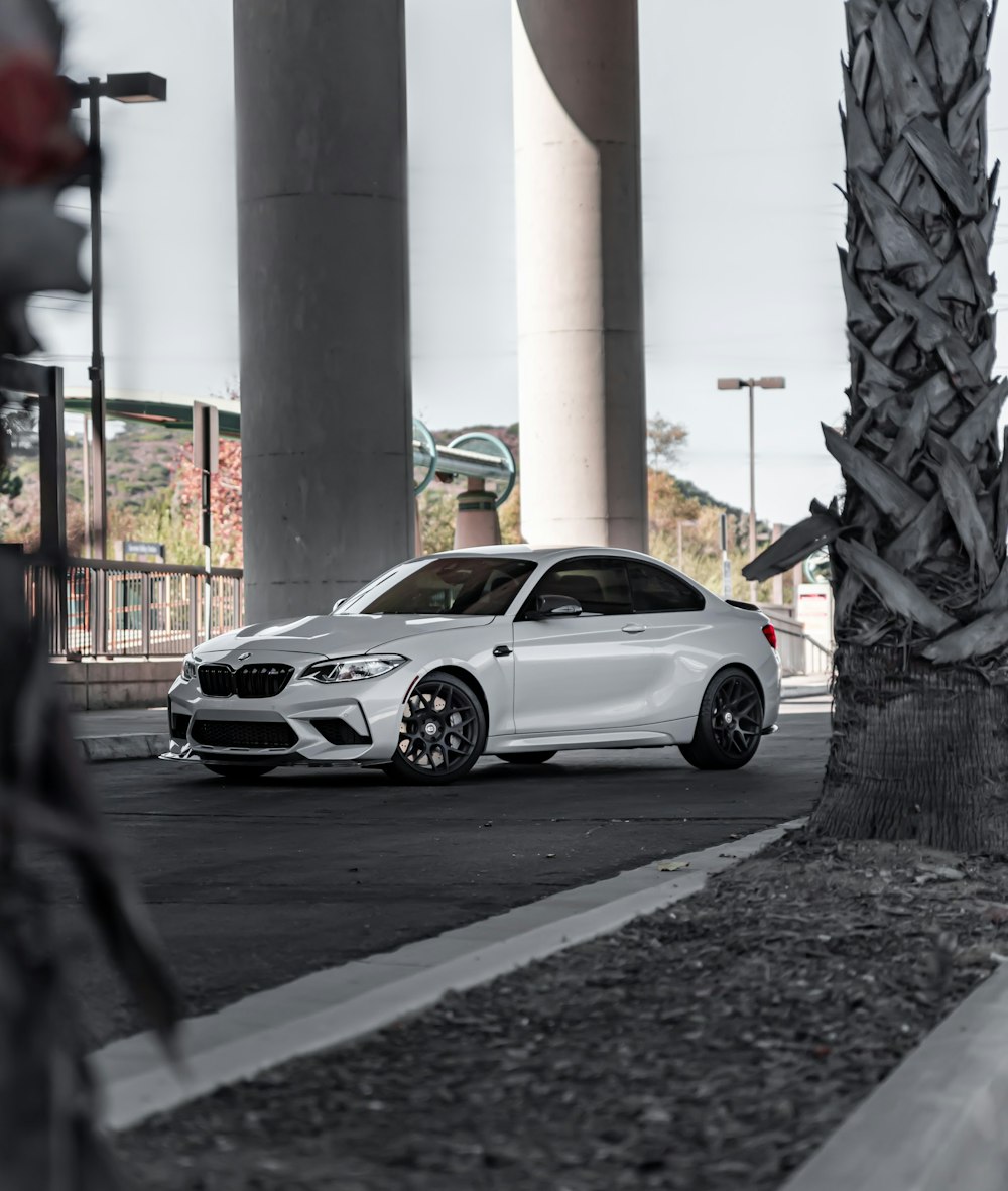 white coupe parked on sidewalk during daytime