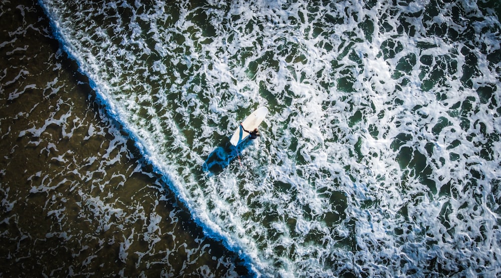 woman in blue bikini lying on white surfboard on beach during daytime