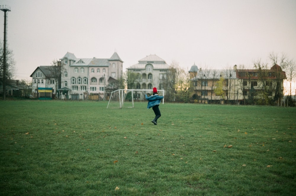 man in blue jacket and black pants walking on green grass field during daytime