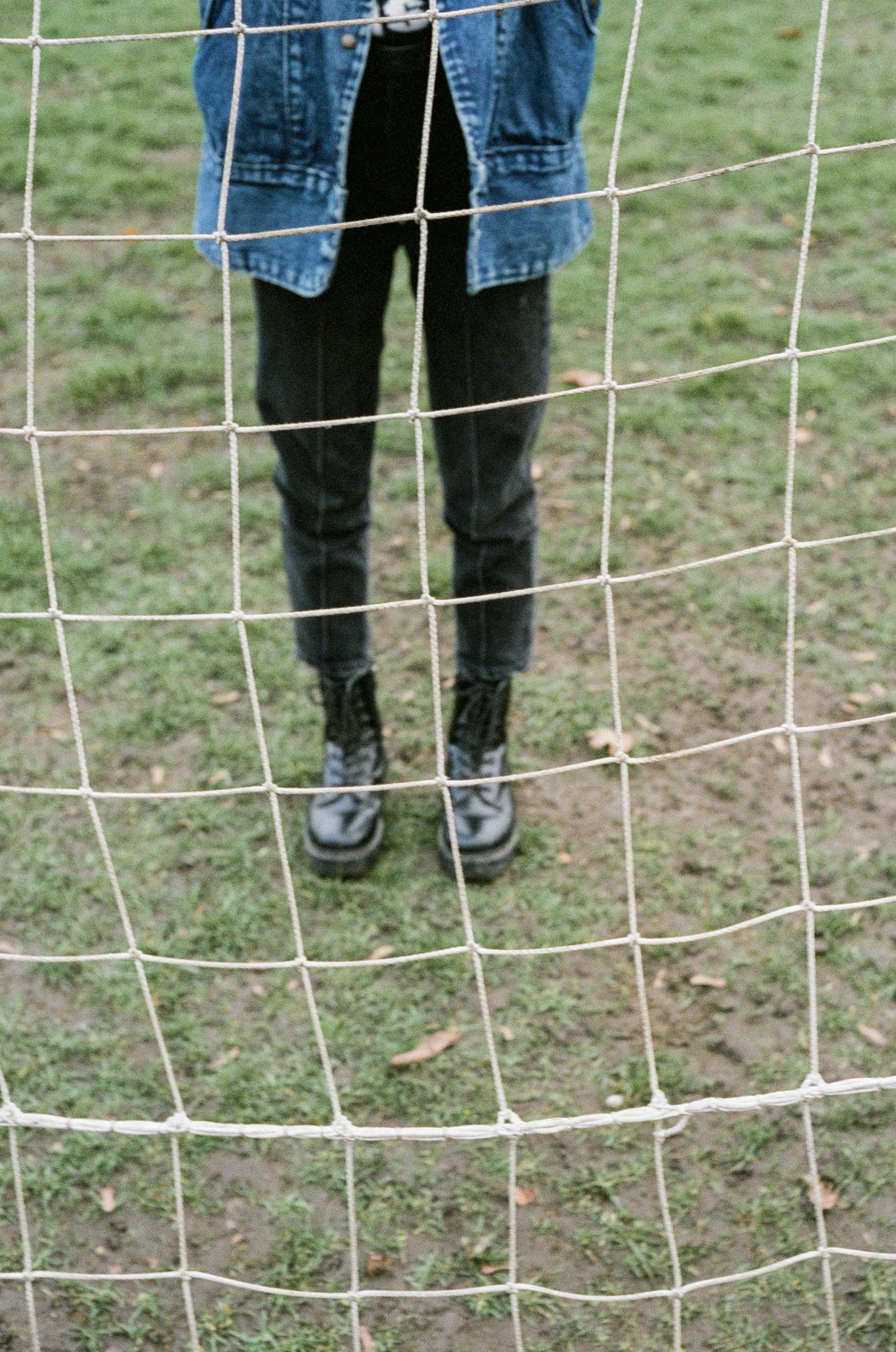 person in blue denim jeans and black boots standing on green grass field during daytime