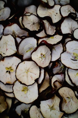 Close-up of vibrant dried apple chips and peaches arranged on rustic wooden board