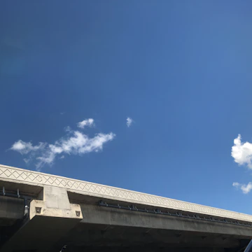 Close-up of fresh concrete being poured into a railway bridge mold on a sunny day.