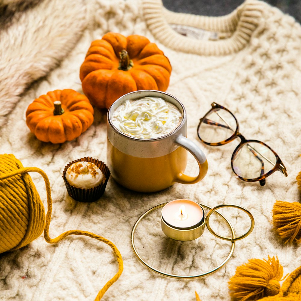 brown ceramic mug with coffee beside orange pumpkin