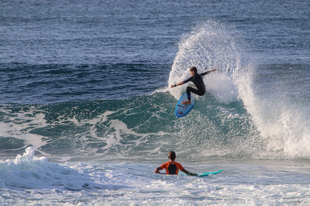 man in blue wetsuit surfing on sea waves during daytime