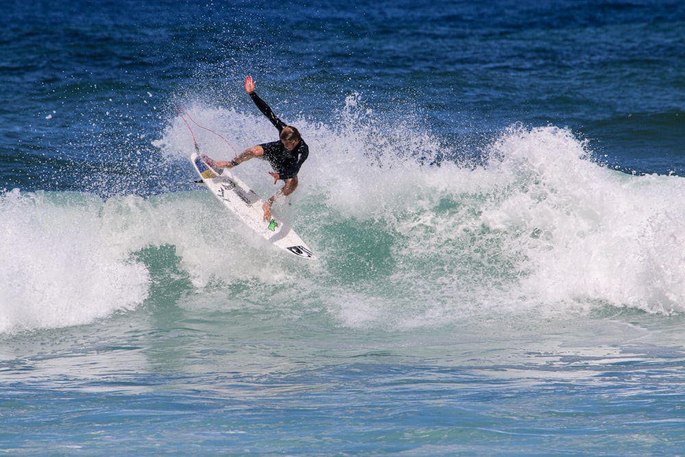 man in black wet suit surfing on sea waves during daytime