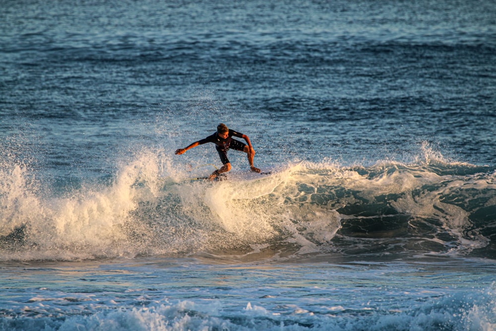 昼間、海の波でサーフィンをする黒いショートパンツの男