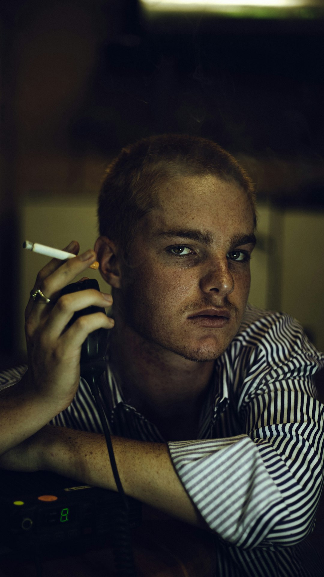 man in black and white stripe shirt smoking cigarette