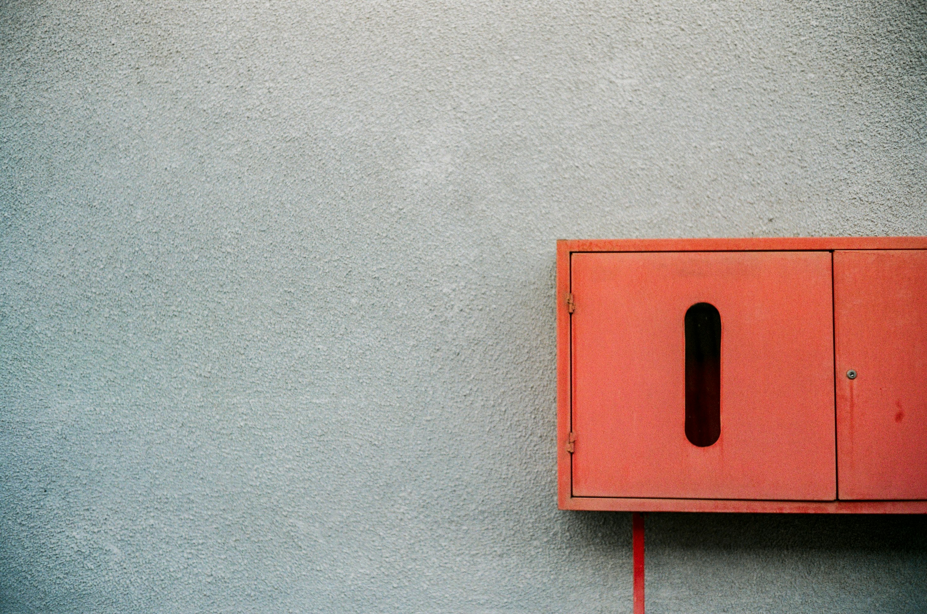 red wooden box mounted on gray concrete wall