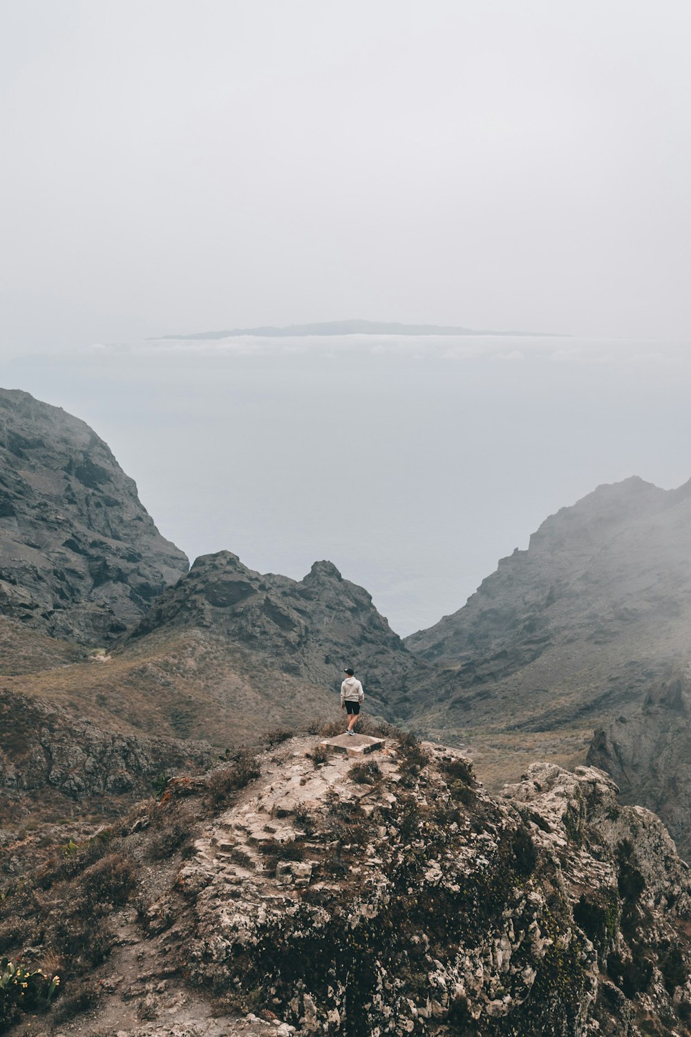 person in white shirt standing on brown rock mountain during daytime