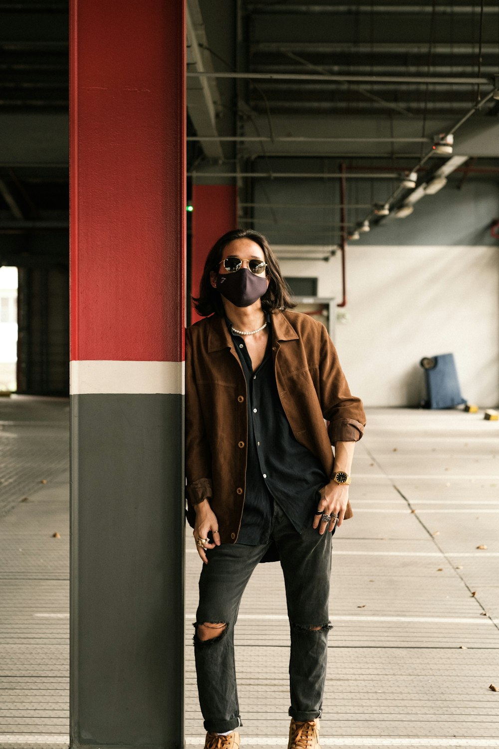 Homme en veste en cuir marron et jean bleu portant des lunettes de soleil noires