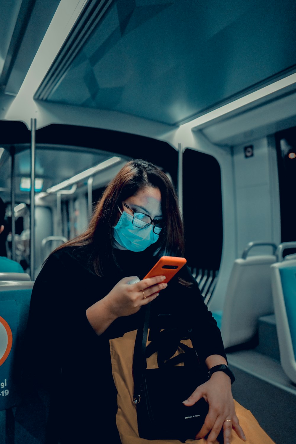 woman in black jacket wearing blue sunglasses holding iphone