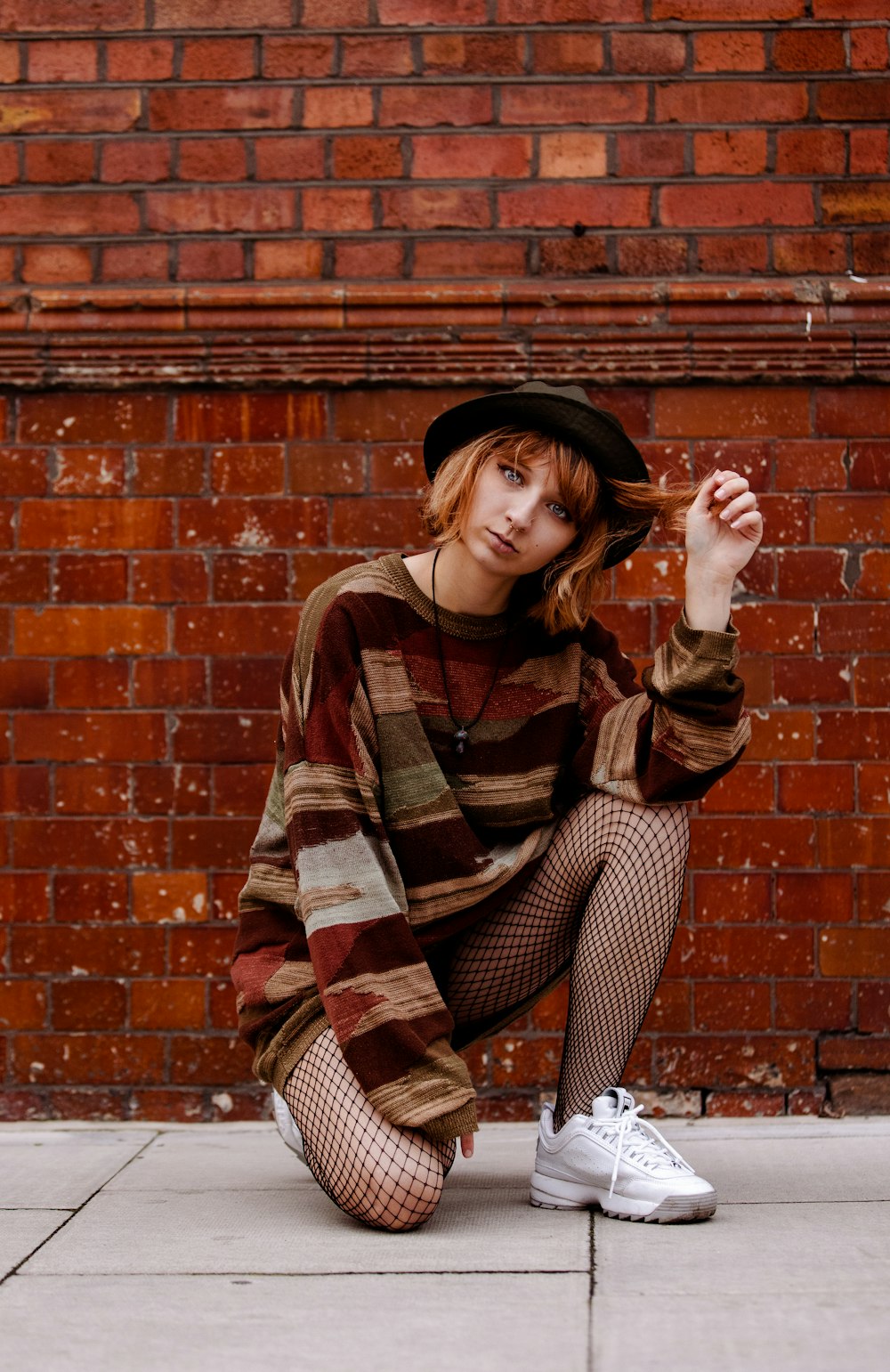 woman in brown and black long sleeve shirt and black and white pants sitting on brown