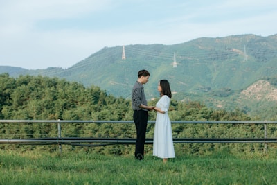 A scenic outdoor shot of a couple holding hands in a field.