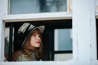 A chic wide-brimmed hat with a delicate ribbon, set against a sunlit window.