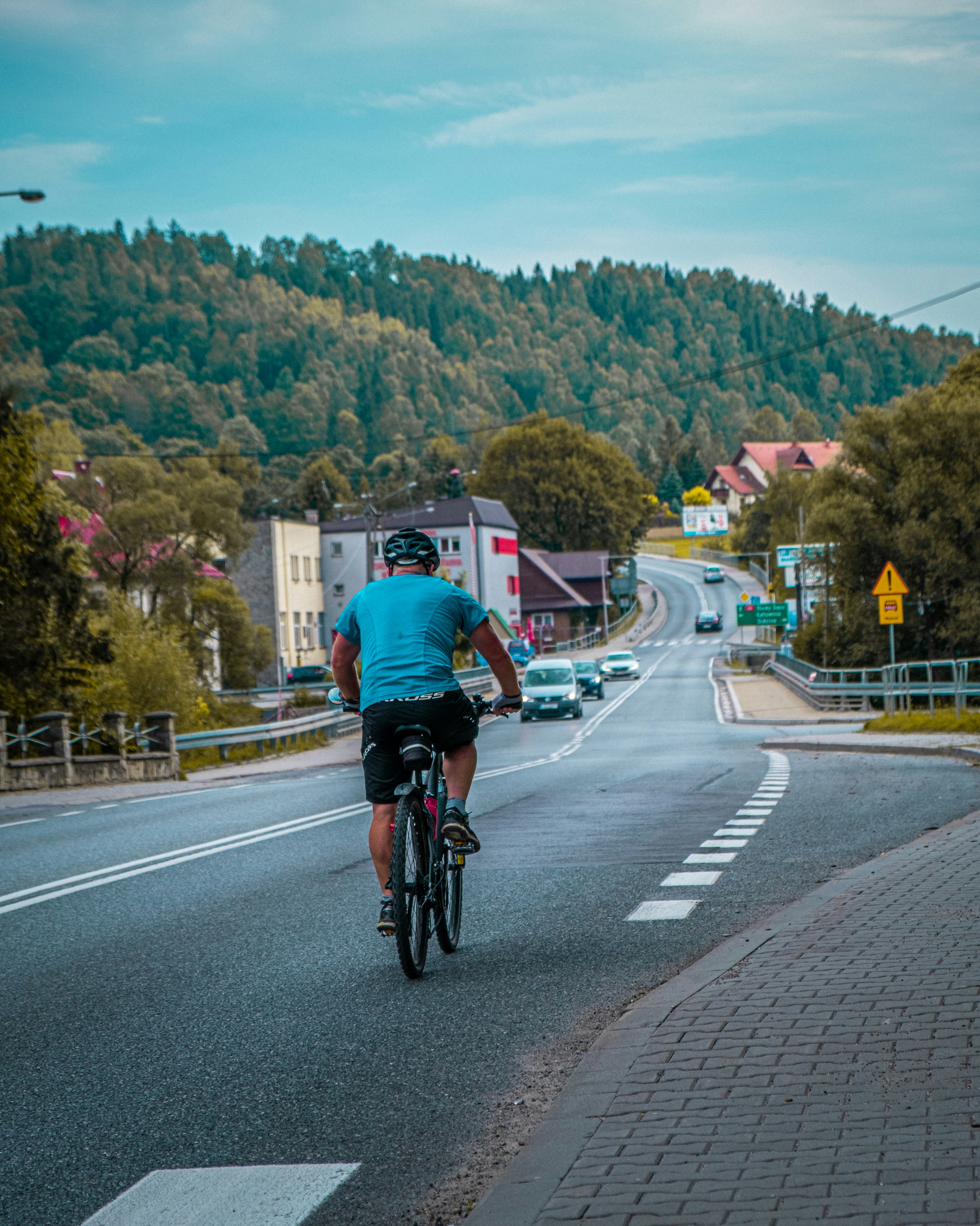 man in red shirt riding bicycle on road during daytime