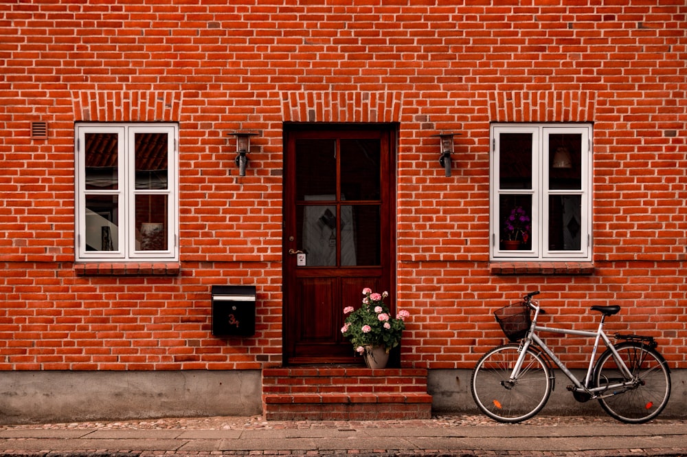 black bicycle parked beside brown brick building