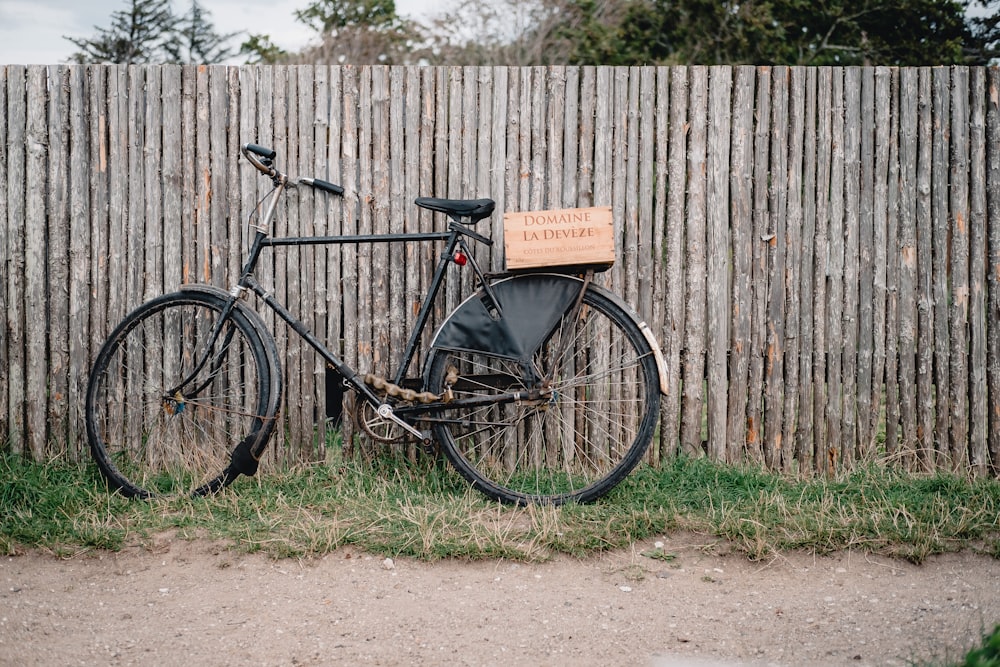 black commuter bike beside wooden fence