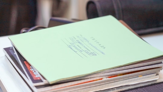 A stack of school papers and a pen on a desk.