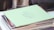 Stack of printed lists and graphic materials on a wooden desk.