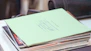 A neat stack of printed presentation handouts on a wooden table.