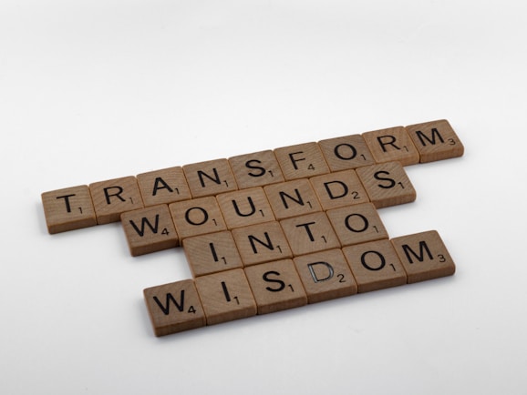 brown wooden blocks on white surface - transform wounds into wisdom