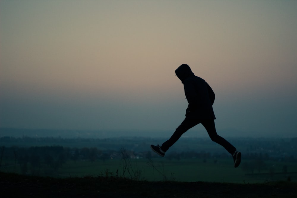 silhouette of man standing on grass field during daytime