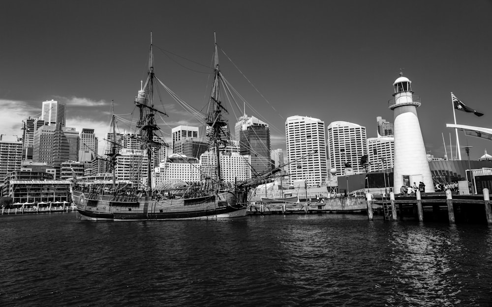 grayscale photo of boat on water near city buildings