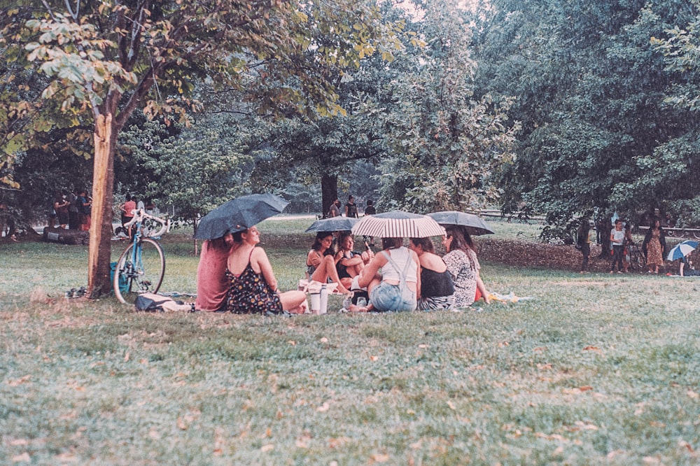 낮에는 녹색 우산 아래 푸른 잔디밭에 앉아 있는 사람들