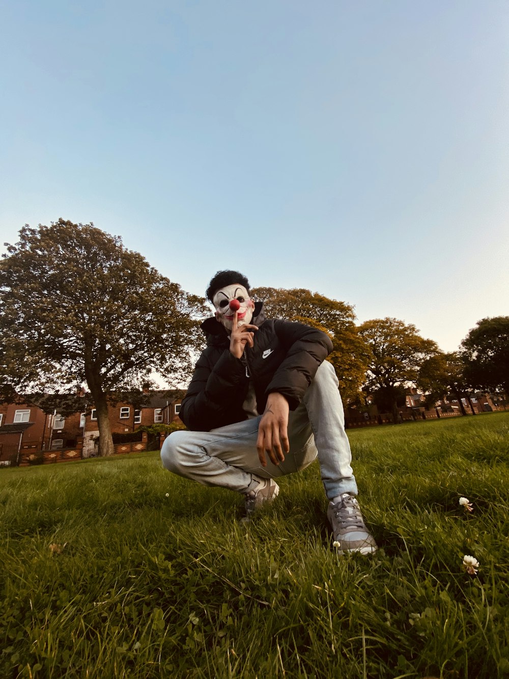 man in black jacket and gray pants sitting on green grass field