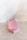 Two bars of pink soap, with one bar leaning against the other on a textured, light-colored surface. The soap has a smooth appearance with small specks, possibly of natural ingredients, and a rough edge on top.