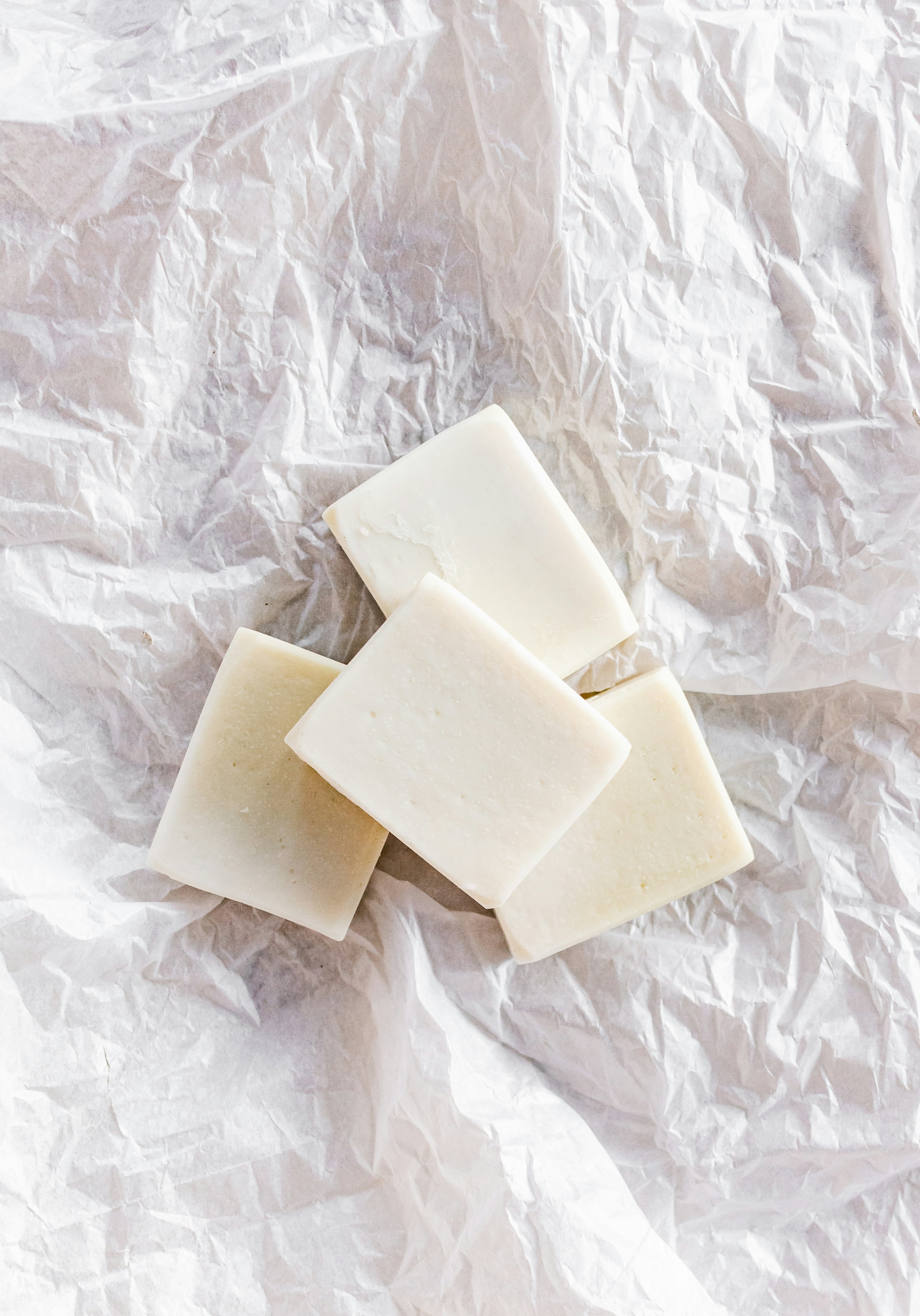 thick slices of gelatinized mayonnaise sitting on crumpled white parchment paper