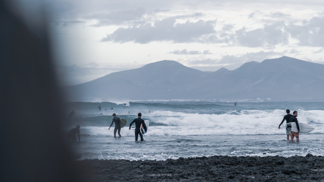 2 men and woman walking on beach during daytime