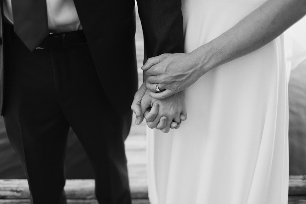 grayscale photo of man and woman holding hands