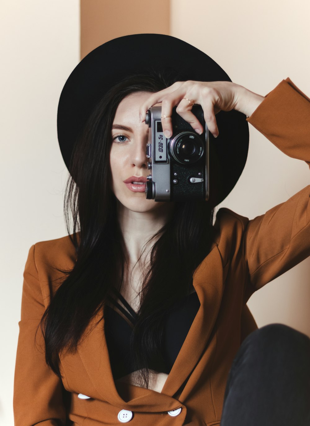 Femme au chapeau noir tenant un appareil photo noir et argenté